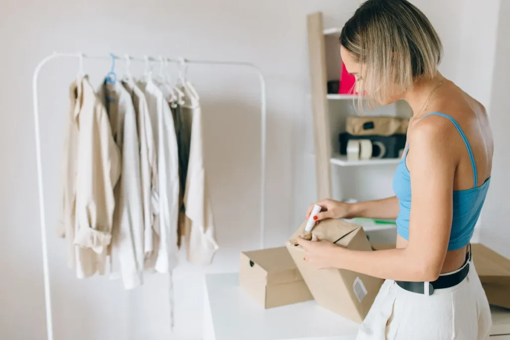 Vrouw pakt kleding in een doos om een online bestelling te retourneren